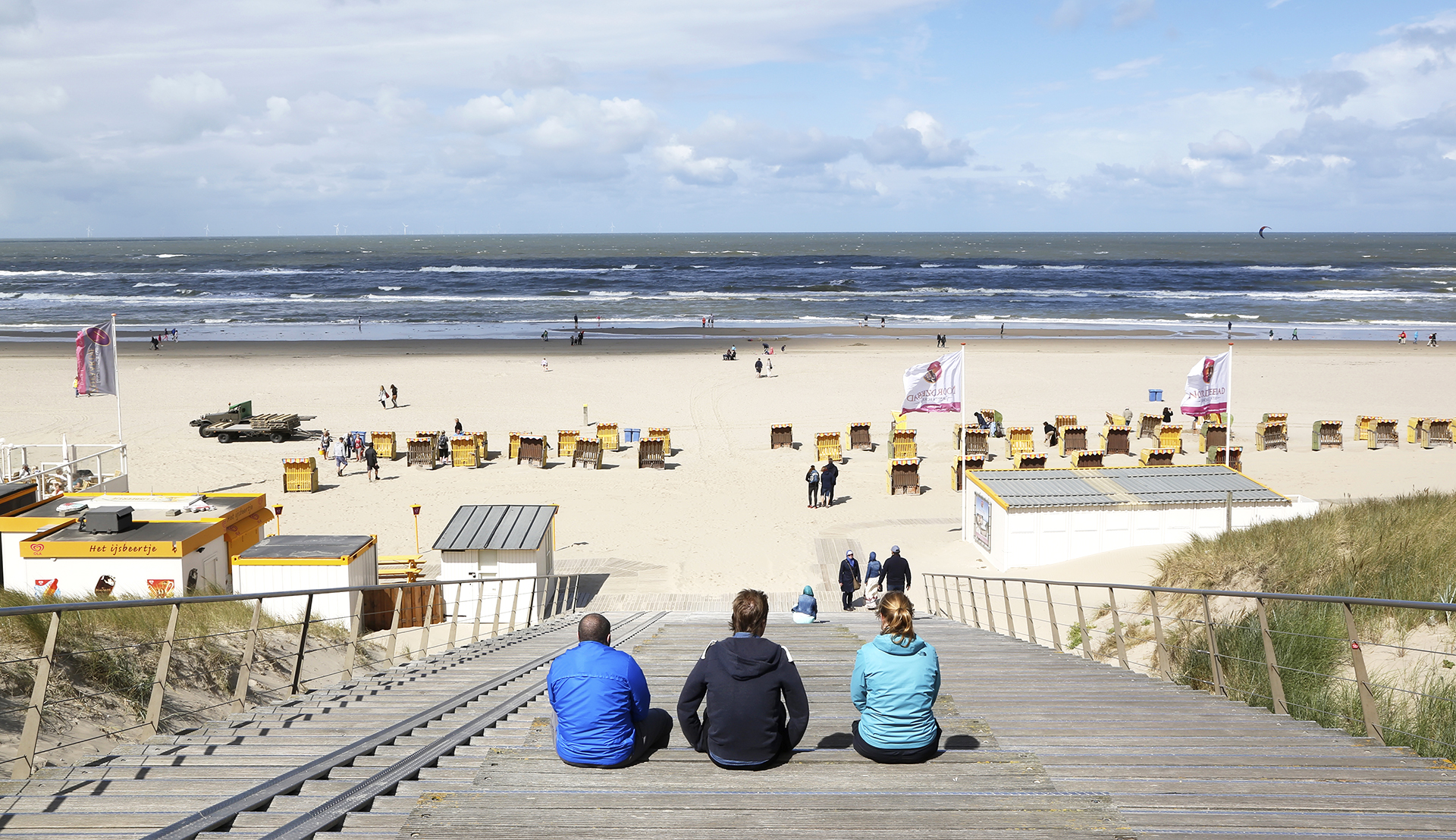 Drie mensen kijken uit over het Strand van Egmond aan Zee Drie mensen kijken uit over het Strand van Egmond aan Zee
