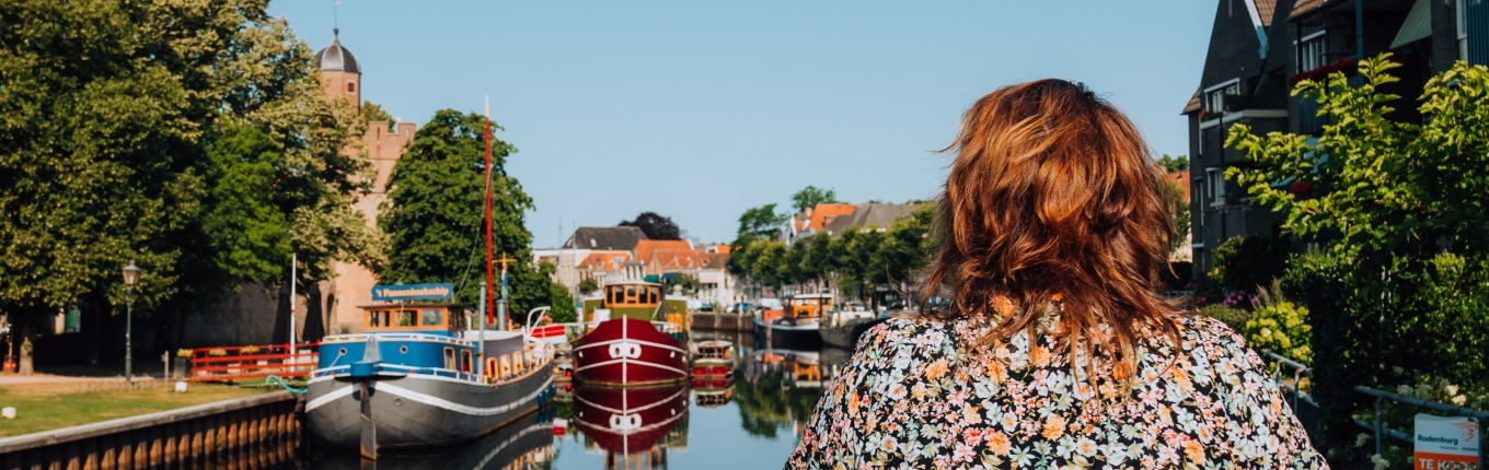 Vrouw kijkt vanaf een bruggetje over een singel in Zwolle