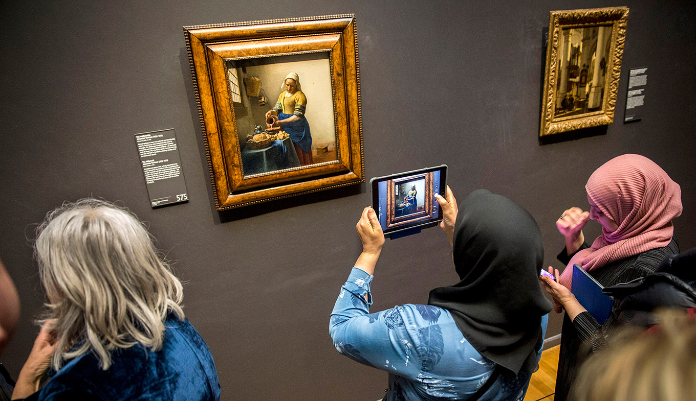 Dame met hoofddoek maakt foto van het Melkmeisje, Johannes Vermeer in het Rijksmuseum 