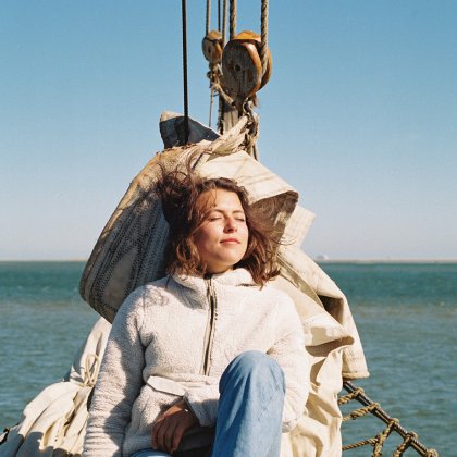 Jonge vrouw relaxed in de zon op een zeilboot in de Waddenzee