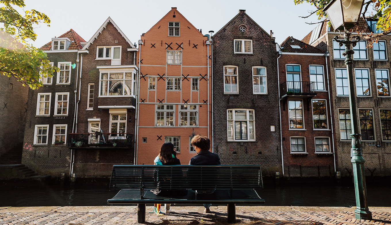 Bezoekers zitten op een bankje in de Grote kerksbuurt te Dordrecht Bezoekers zitten op een bankje in de Grote kerksbuurt te Dordrecht