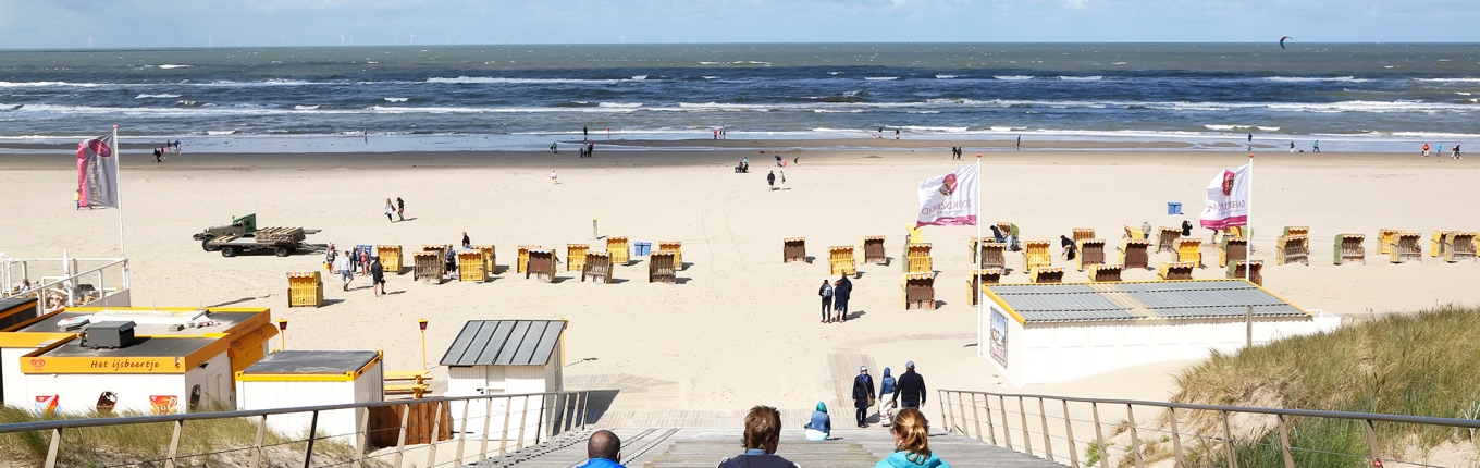 Drie mensen kijken uit over het Strand van Egmond aan Zee