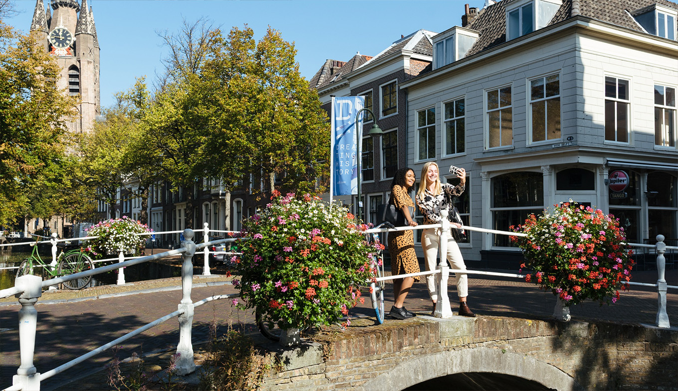 Twee vrouwen maken foto's in Delft. Selfie met gracht en Oude Kerk